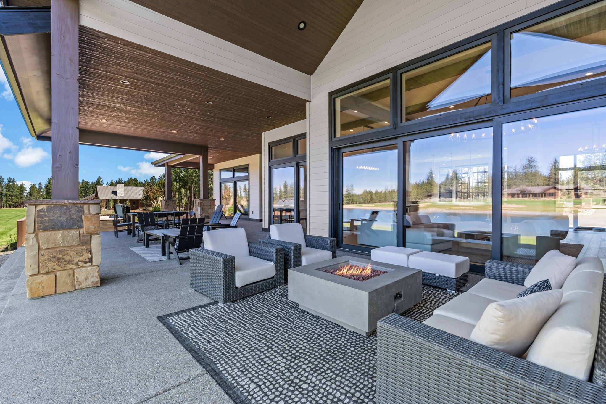 The covered outdoor patio is made for gathering — dining for 8, natural gas fire pit, private hot tub, space heater, and a natural gas BBQ, all with Tanager Lake as your backdrop.