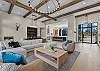 Every seat in the house has a view — the open living room offers comfortable seating for the whole group, a gas fireplace, and Tanager Lake as the backdrop.