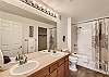 Ensuite bathroom connected to the king bedroom, featuring a shower/tub combo and double vanities.