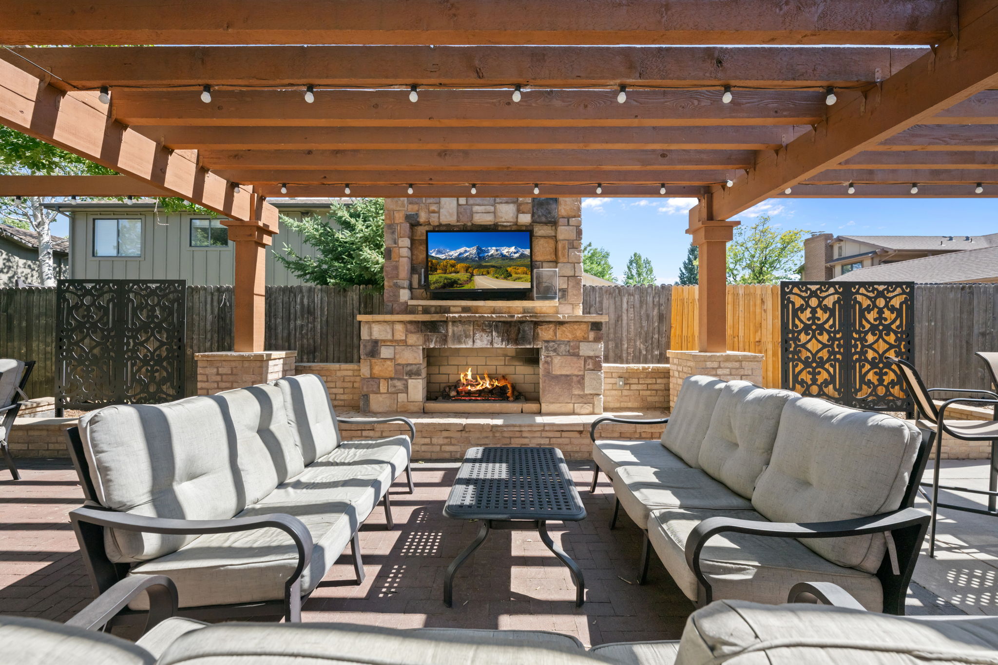 Community outdoor pergola with stone fireplace, outdoor TV, and grill. 