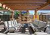 Community outdoor pergola with stone fireplace, outdoor TV, and grill. 