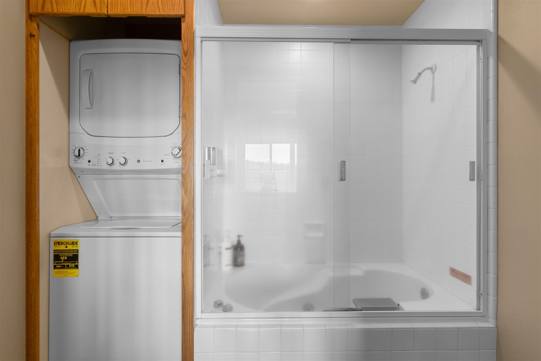 King main bathroom with a combo tub/shower and a stacked laundry setup. 