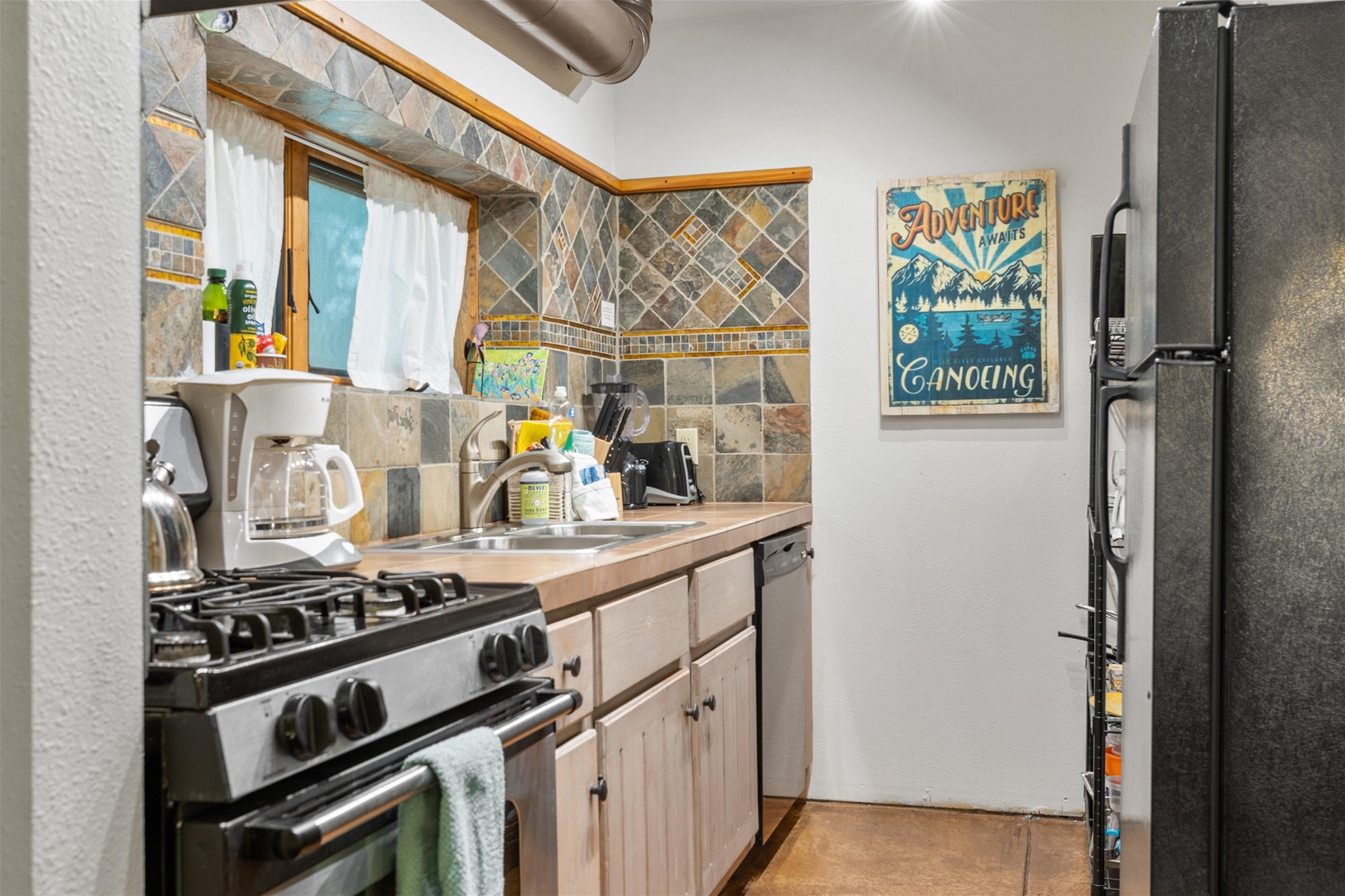 Quaint kitchen featuring a gas range, dishwasher, full-size refrigerator, and coffee maker.