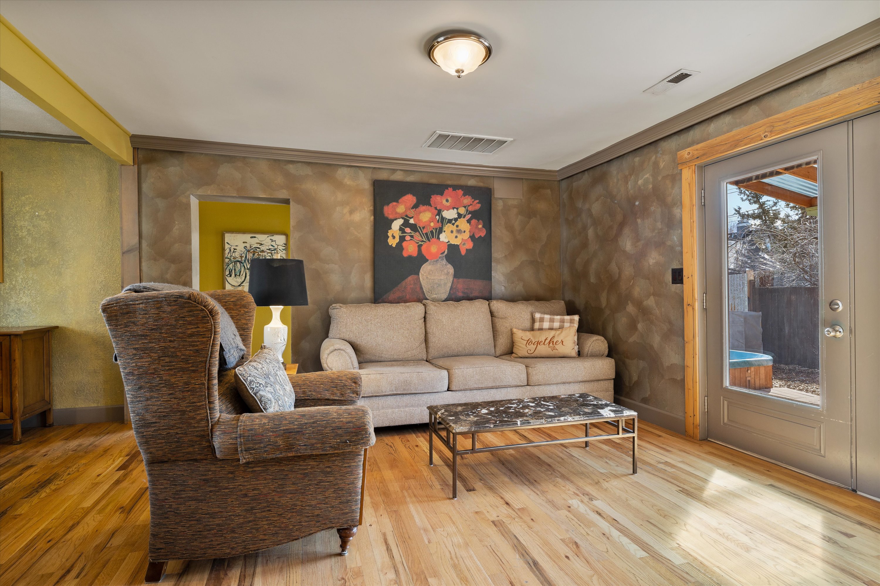 Sunny open living room with sofa, smart TV, and easy chair. 