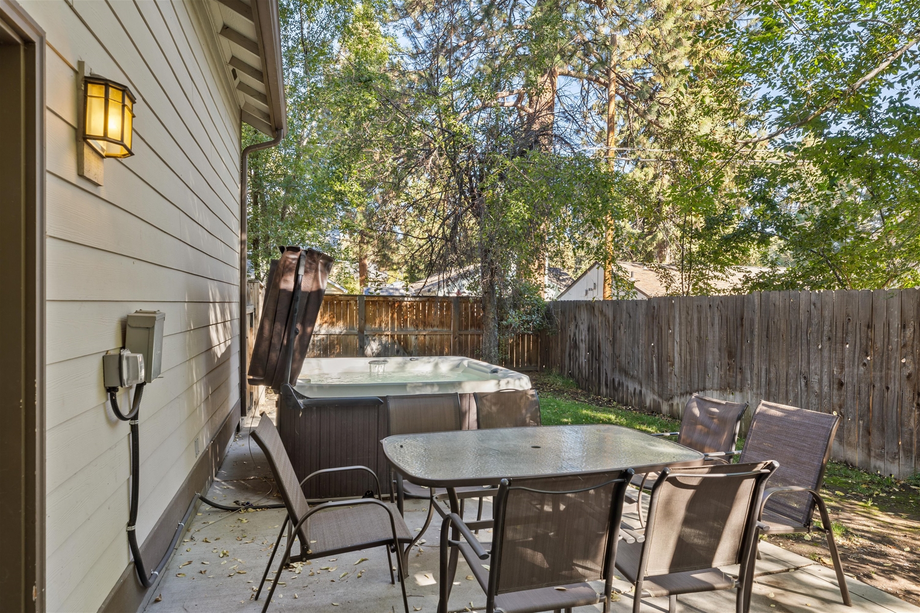 Fenced backyard with outdoor dining area and hot tub. 