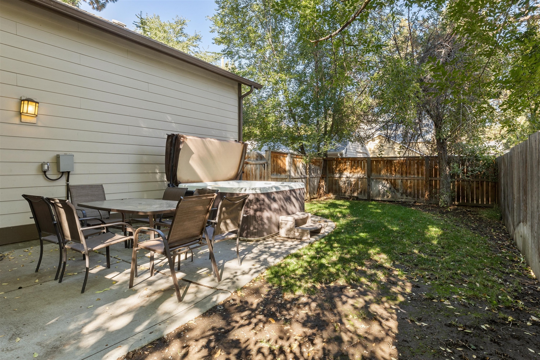Fenced backyard with outdoor dining area and hot tub. 