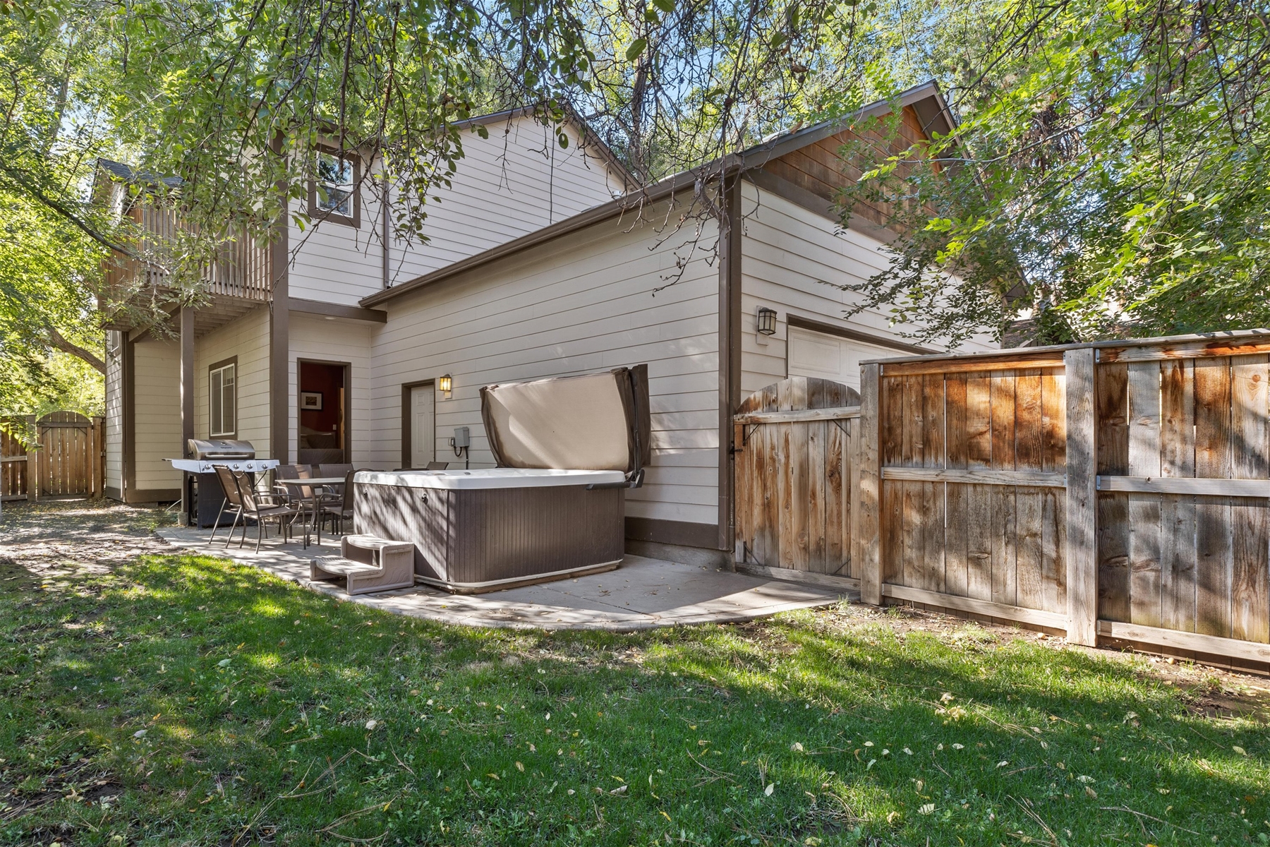Fenced backyard with outdoor dining area and hot tub. 