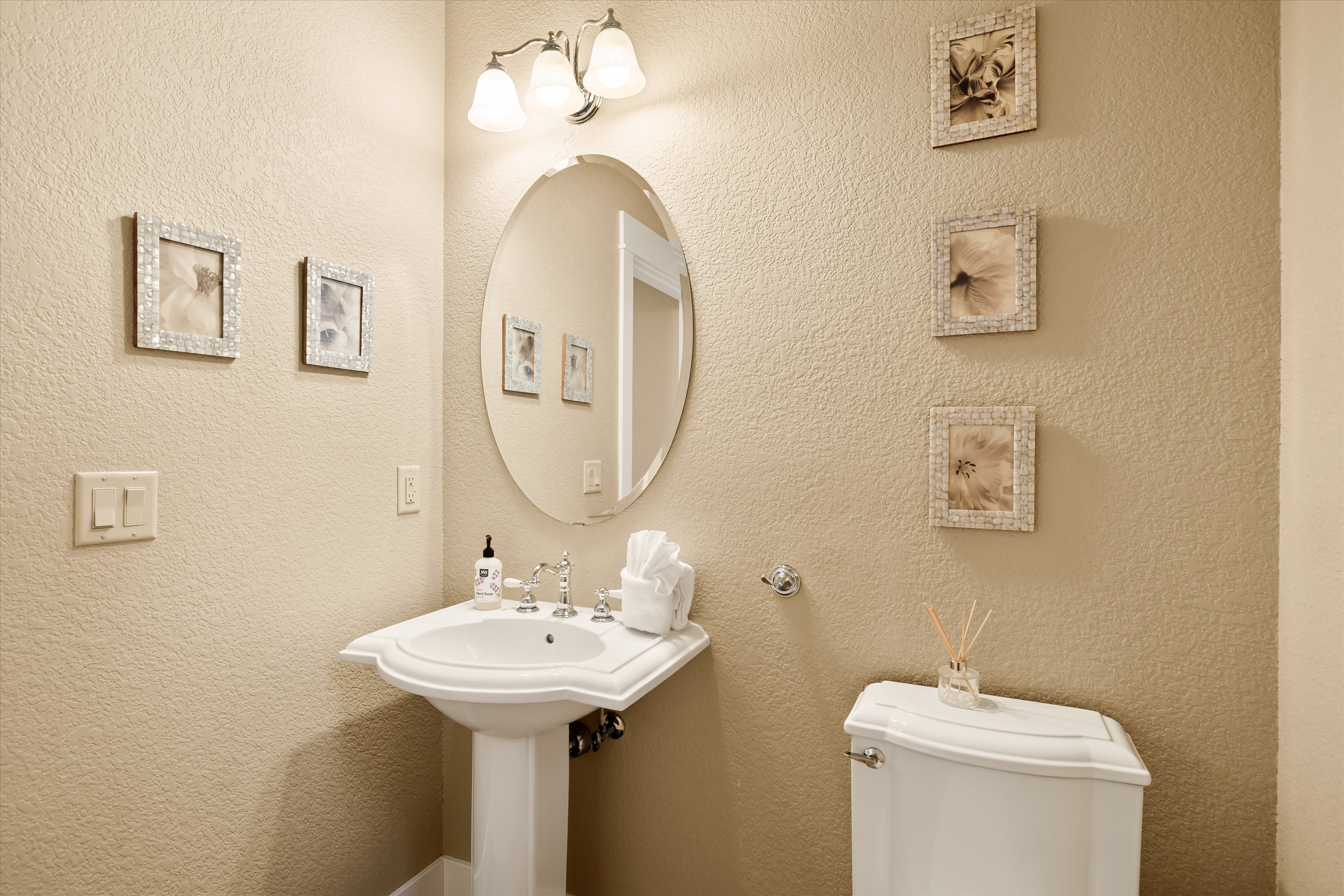 Powder room with pedestal sink and oval mirror. 