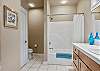 Guest bathroom with tub/shower combo and tile floors.