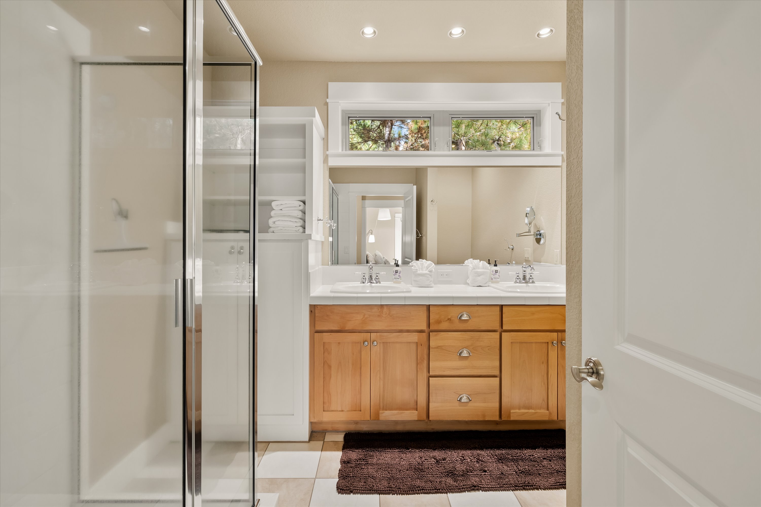 Private en-suite bathroom with glass shower and wood vanity.