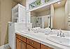 Full bathroom with dual sinks, wood vanity, and glass shower.