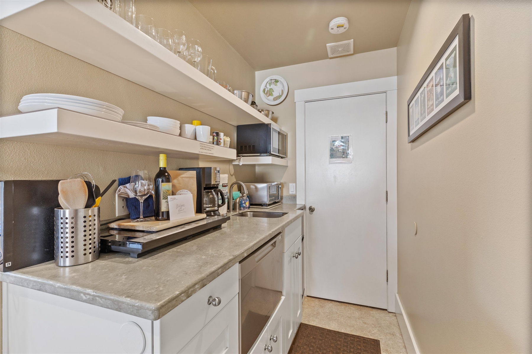 The small, but mighty kitchen area is equipped with a small refrigerator, dishwasher, coffee maker, microwave, toaster oven (no conventional oven) and a two-burner “induction” cooktop.