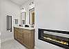 Our primary ensuite bathroom features a pass-through gas fireplace, a dual vanity, and a large walk-in glass shower.