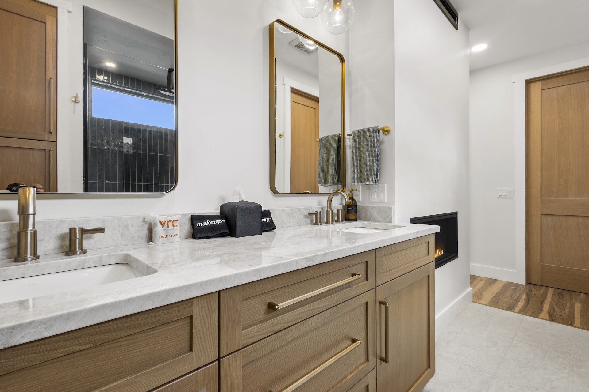 Our primary ensuite bathroom features a pass-through gas fireplace, a dual vanity, and a large walk-in glass shower.