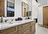Our primary ensuite bathroom features a pass-through gas fireplace, a dual vanity, and a large walk-in glass shower.