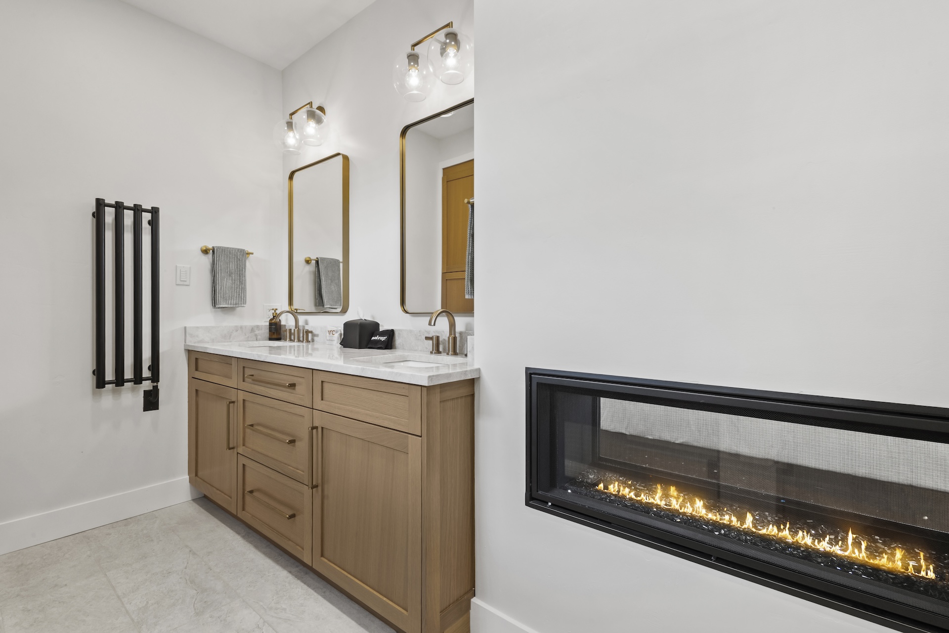 Our primary ensuite bathroom features a pass-through gas fireplace, a dual vanity, and a large walk-in glass shower.