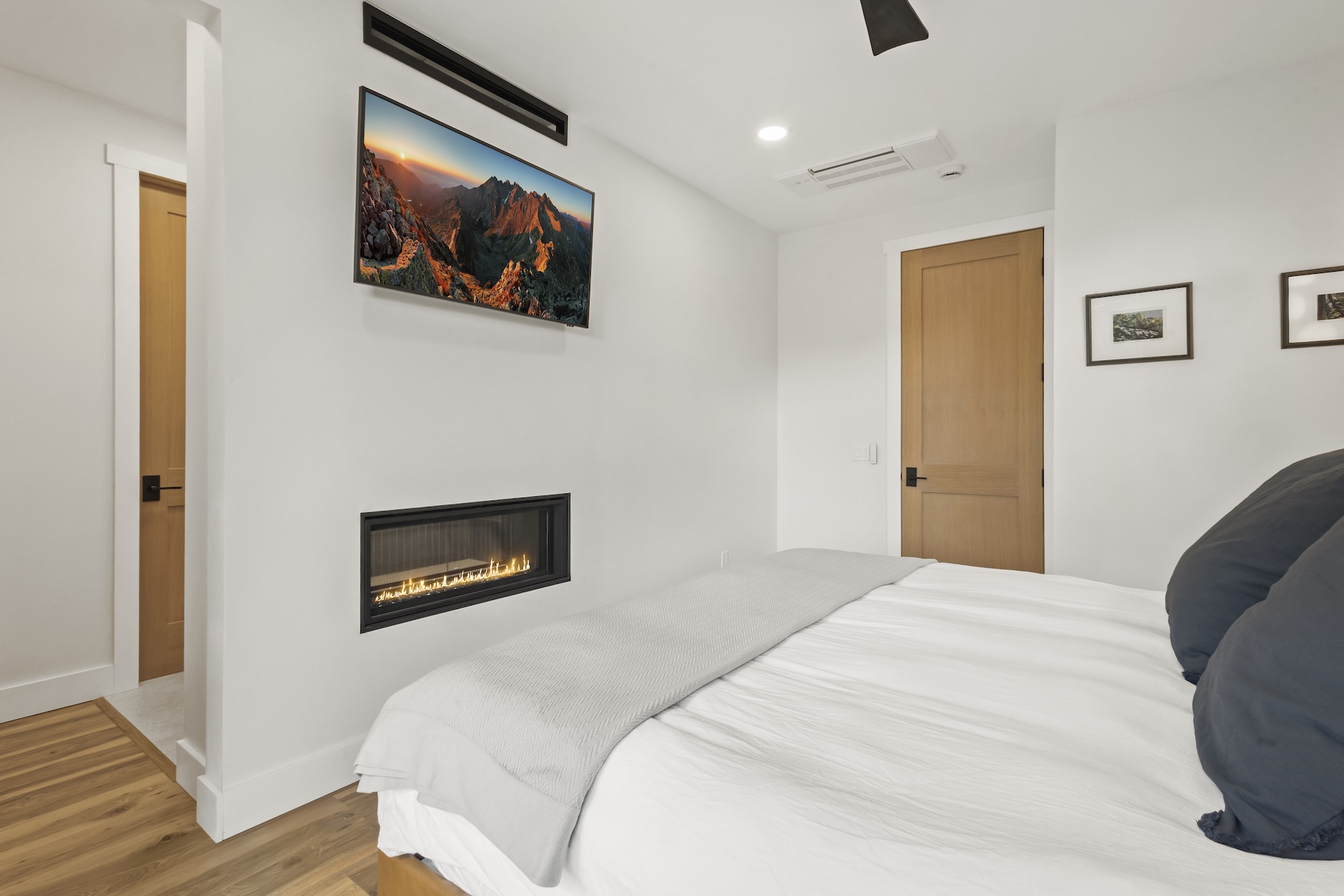 Retreat to the elegant primary bedroom, featuring a plush king bed, a private balcony, pass-through gas fireplace, Smart TV and large ensuite bathroom. 