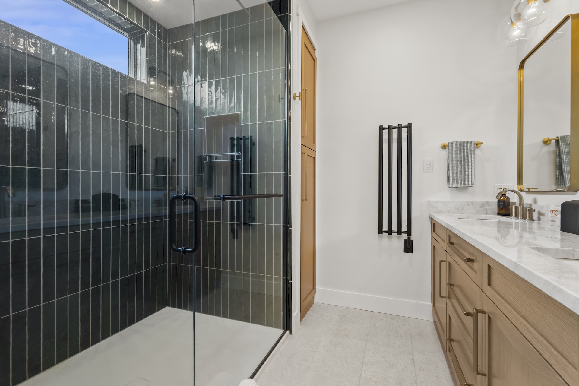 Our primary ensuite bathroom features a pass-through gas fireplace, a dual vanity, and a large walk-in glass shower.