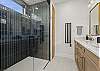 Our primary ensuite bathroom features a pass-through gas fireplace, a dual vanity, and a large walk-in glass shower.