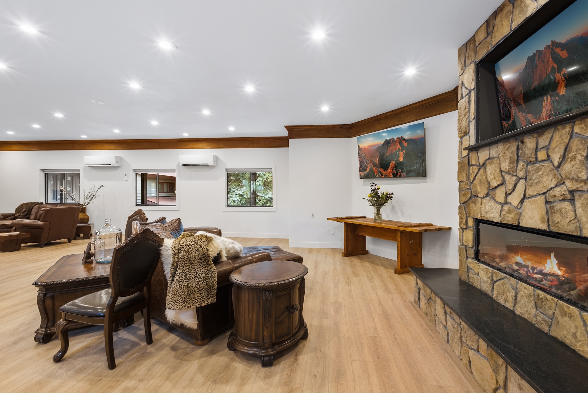 Great room with large fireplace, smart TV, dining space for 14 people, lounging areas, antique piano, and bar. 