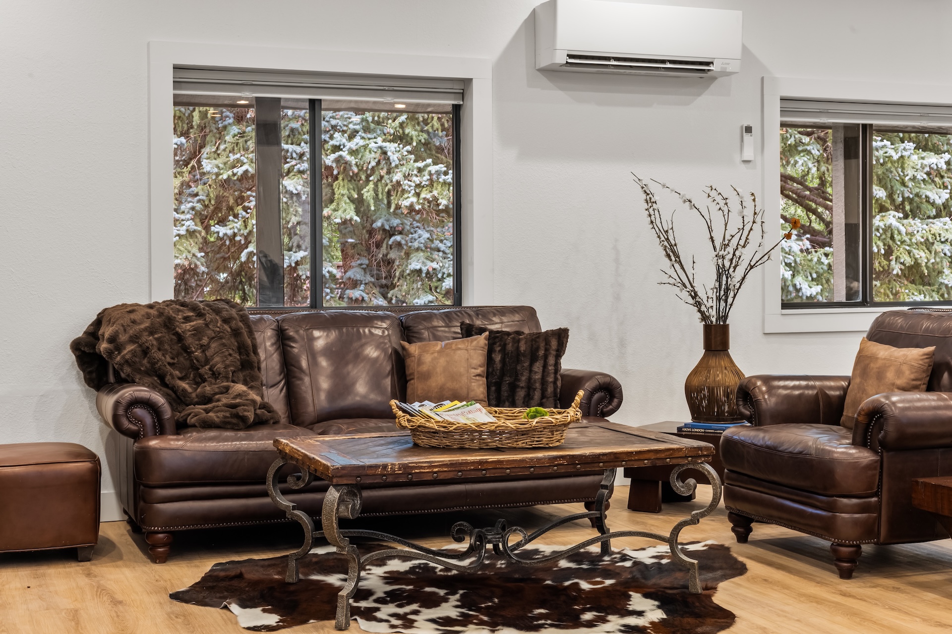 Great room with large fireplace, smart TV, dining space for 14 people, lounging areas, antique piano, and bar. 