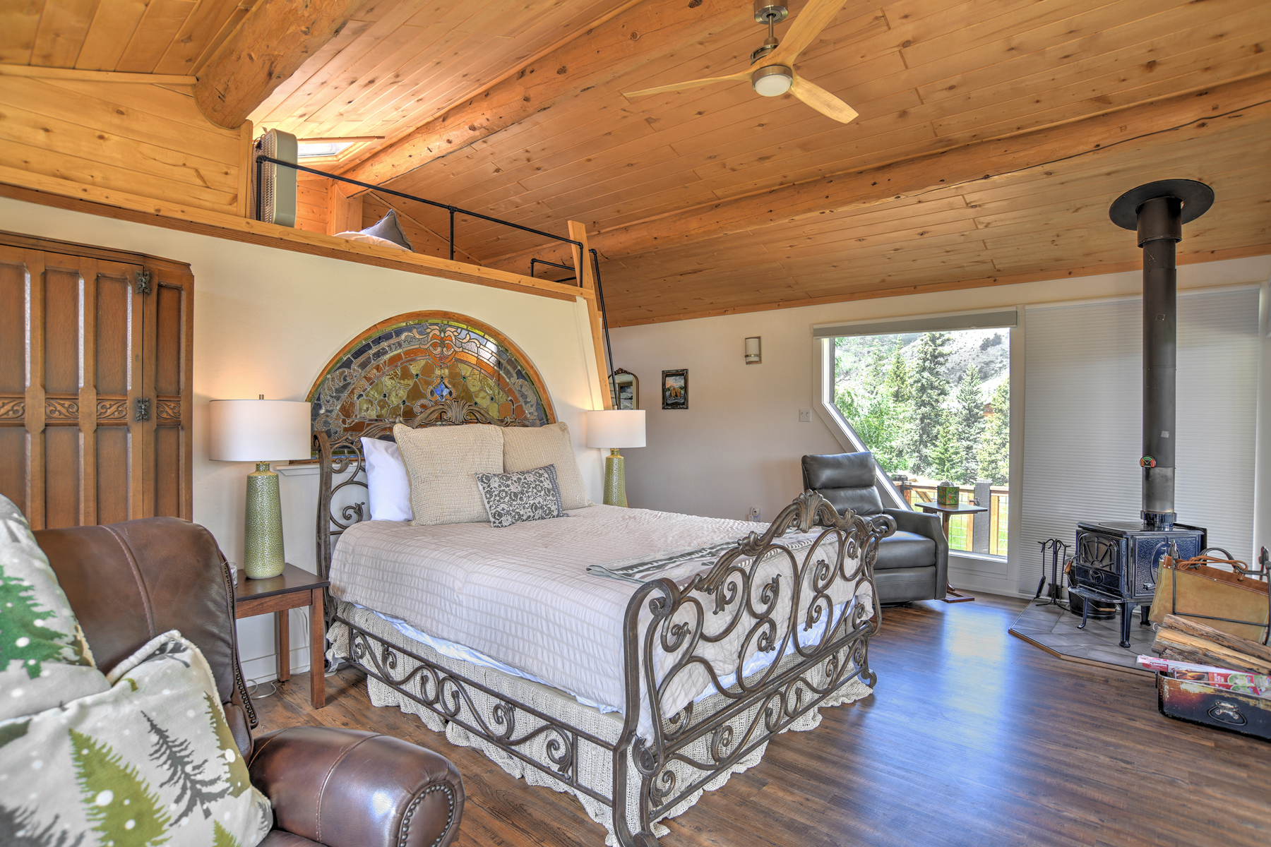 Main bedroom with king bed, wood stove, queen loft bed above (not private) and with access to the large deck. ,