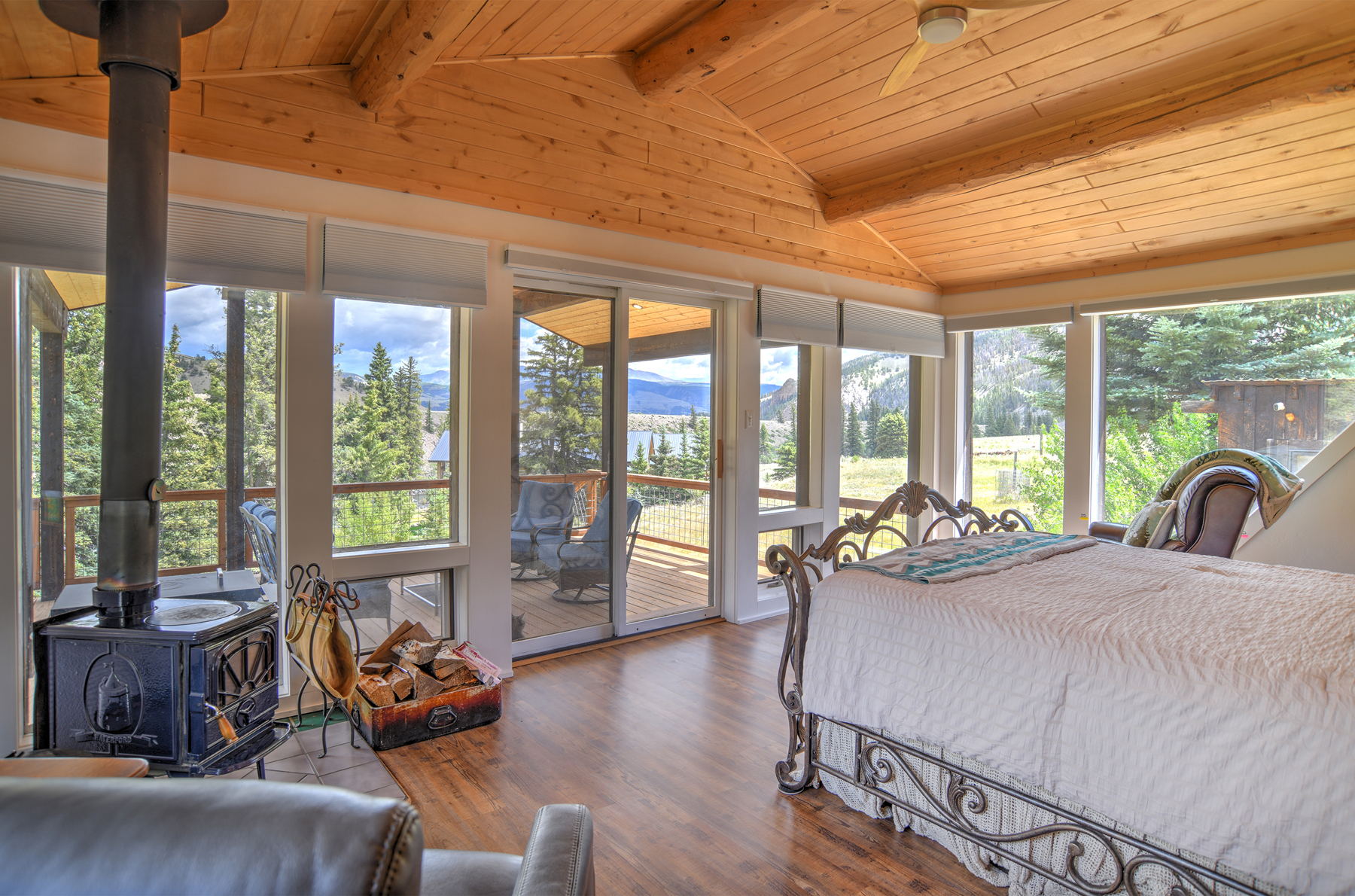 King bedroom with woodstove, two recliners, lots of windows, incredible views, and deck access.