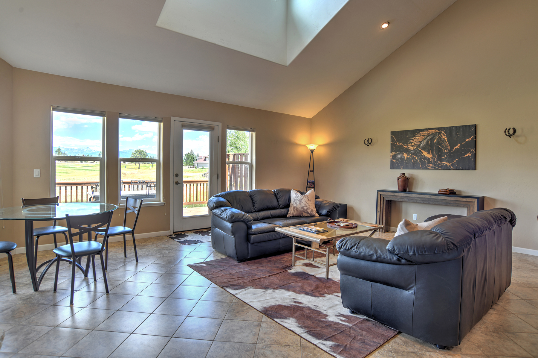 Open living room with lots of natural light, mountain and golf course views. With a gas fireplace and comfortable seating. 