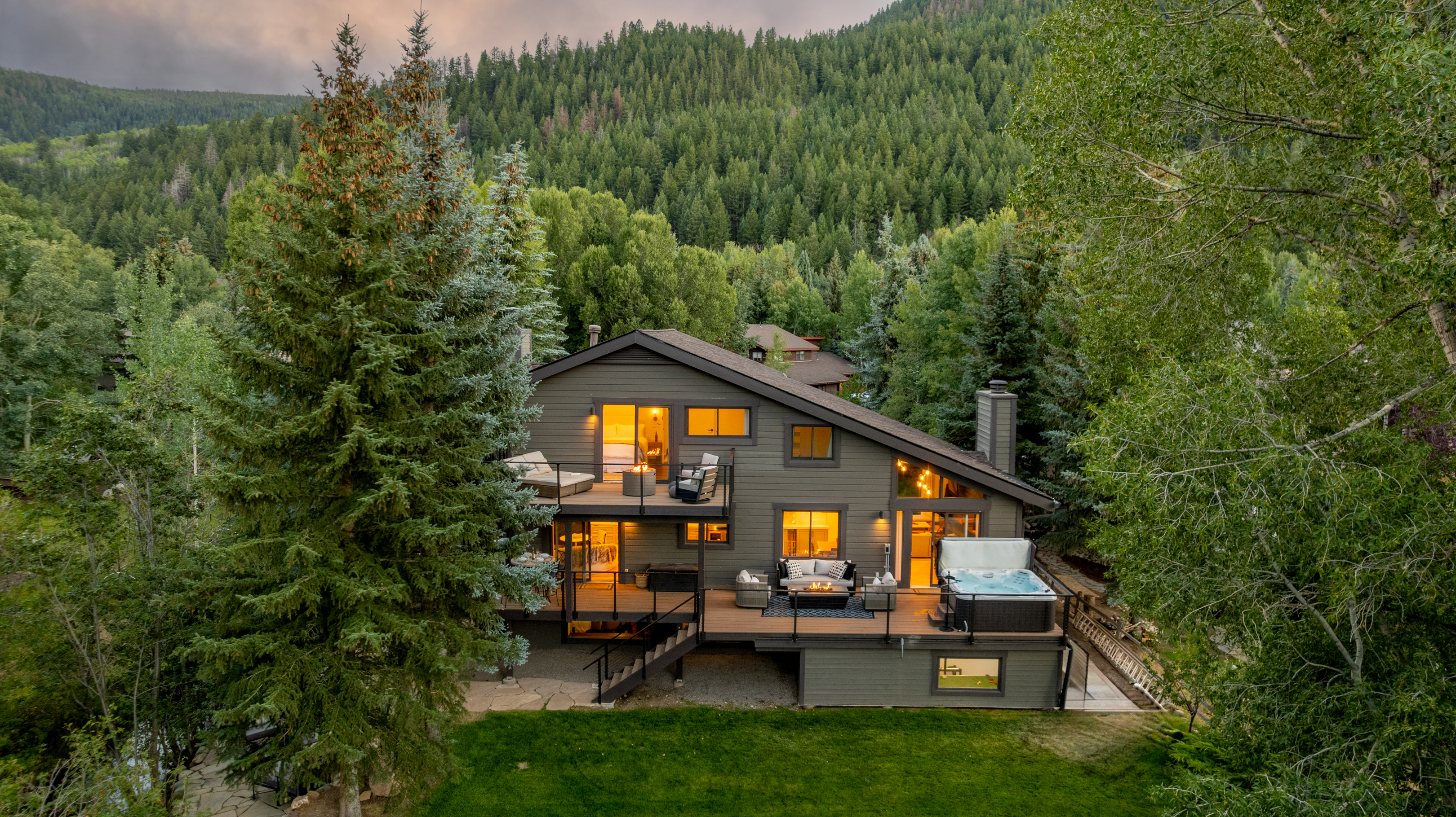 Ariel view of the home including multiple decks, 2 outdoor fire pits, an 8-person hot tub, backyard and creekside views