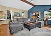 Game room with a regulation shuffleboard table, sectional sofa, smart TV, and a library of movies and games.