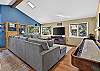 Game room with a regulation shuffleboard table, sectional sofa, smart TV, and a library of movies and games.