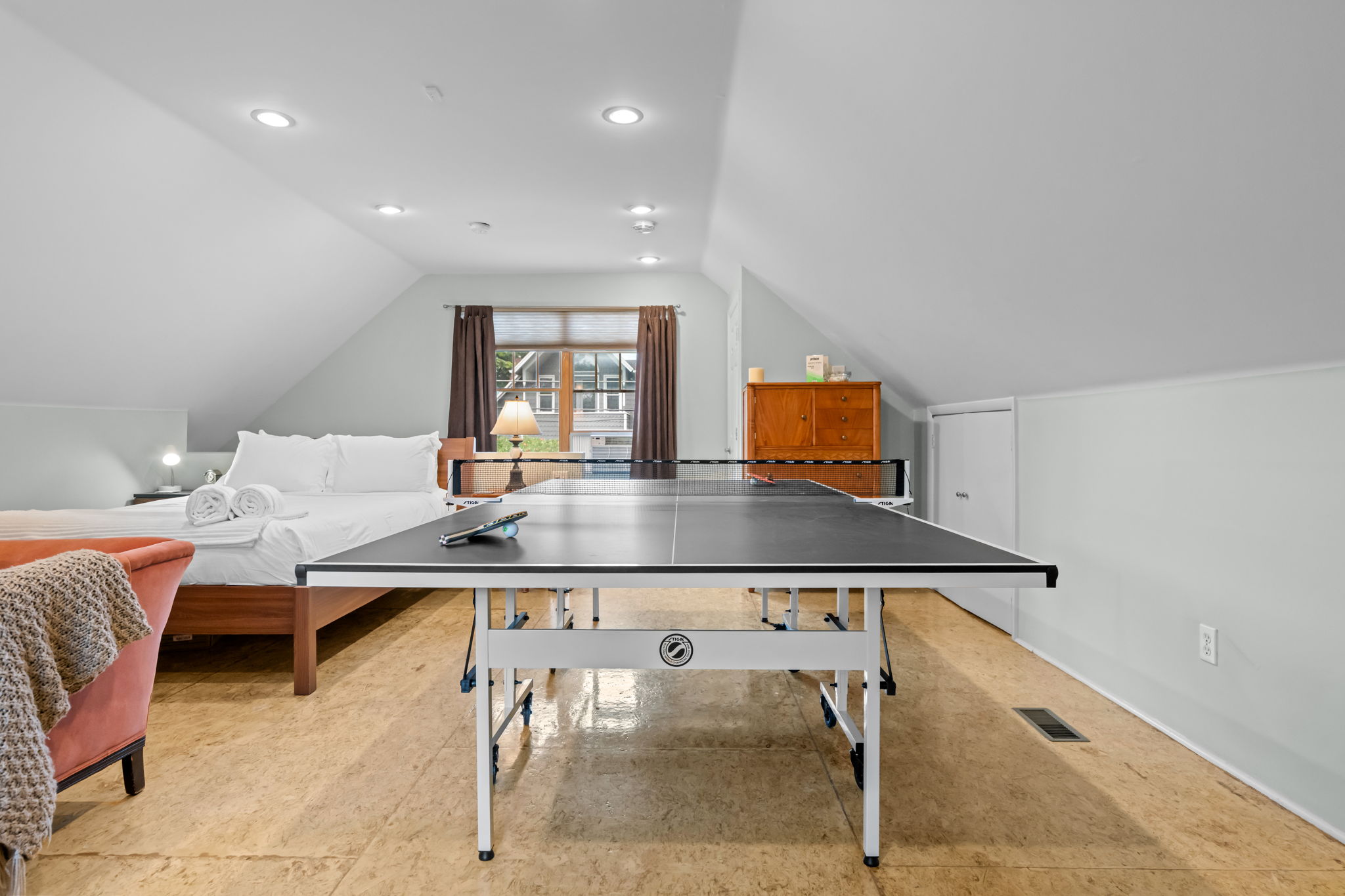 Bedroom with queen bed, living area, smart TV, and ping pong table.