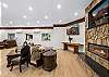 Great room with large fireplace, two Smart TVs, dining space for 14 people, lounging areas, antique piano, pool table, and bar. 
