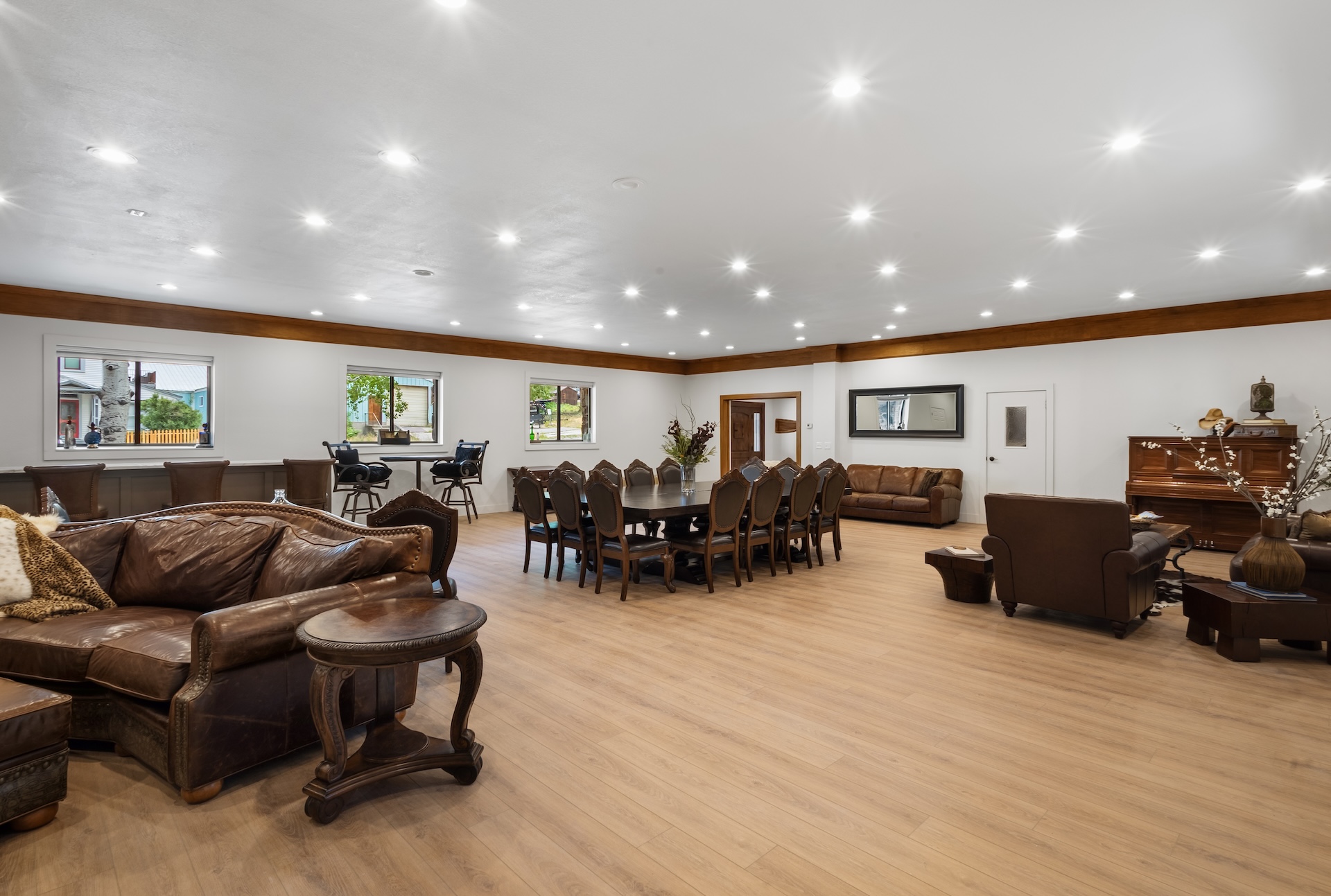 Great room with large fireplace, two Smart TVs, dining space for 14 people, lounging areas, antique piano, pool table, and bar. 