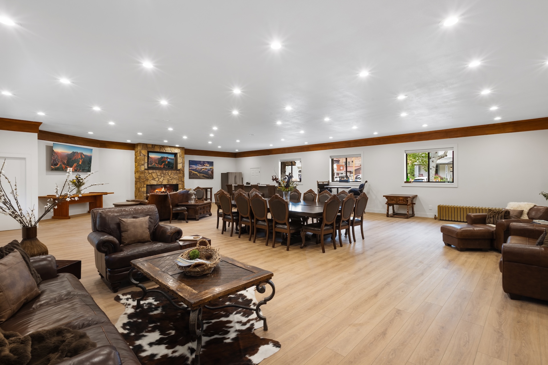 Great room with large fireplace, two Smart TVs, dining space for 14 people, lounging areas, antique piano, pool table, and bar. 