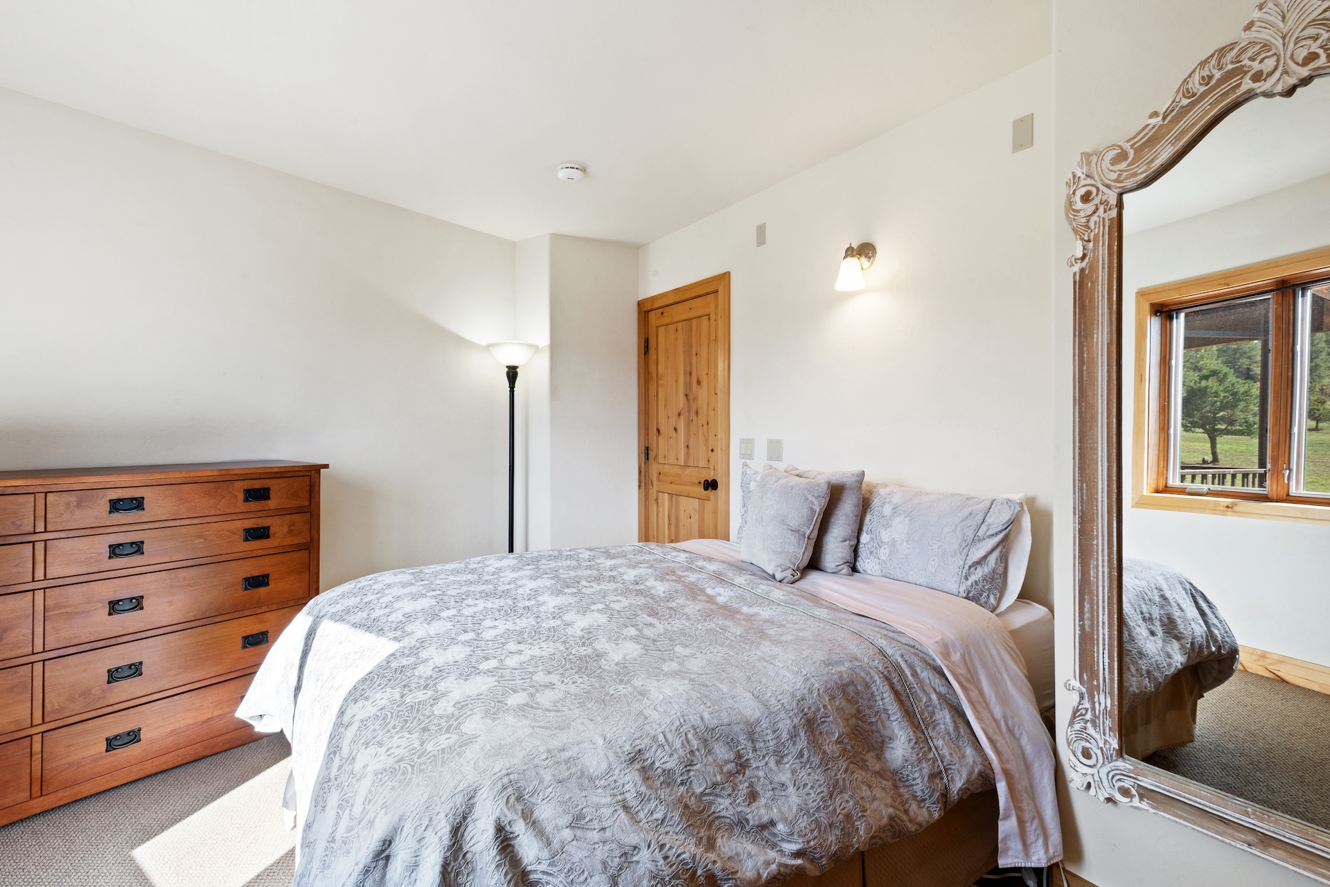 The guest bedroom includes a comfortable queen bed with a large mirror, closet, dresser, and mountain views. 