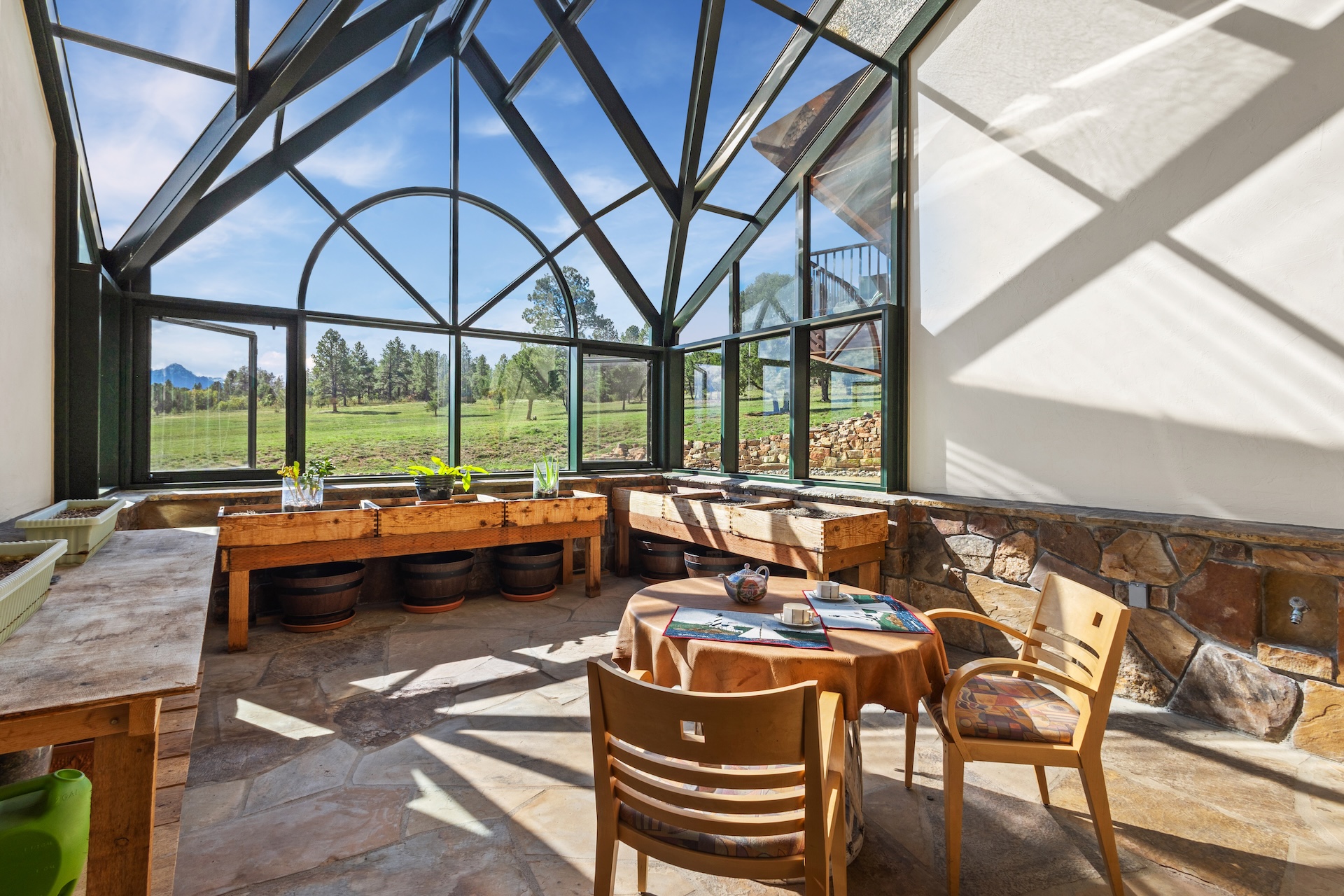 The all-glass greenhouse with a café table is the perfect spot to enjoy morning coffee or watch the stars.