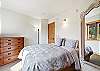 The guest bedroom includes a comfortable queen bed with a large mirror, closet, dresser, and mountain views. 