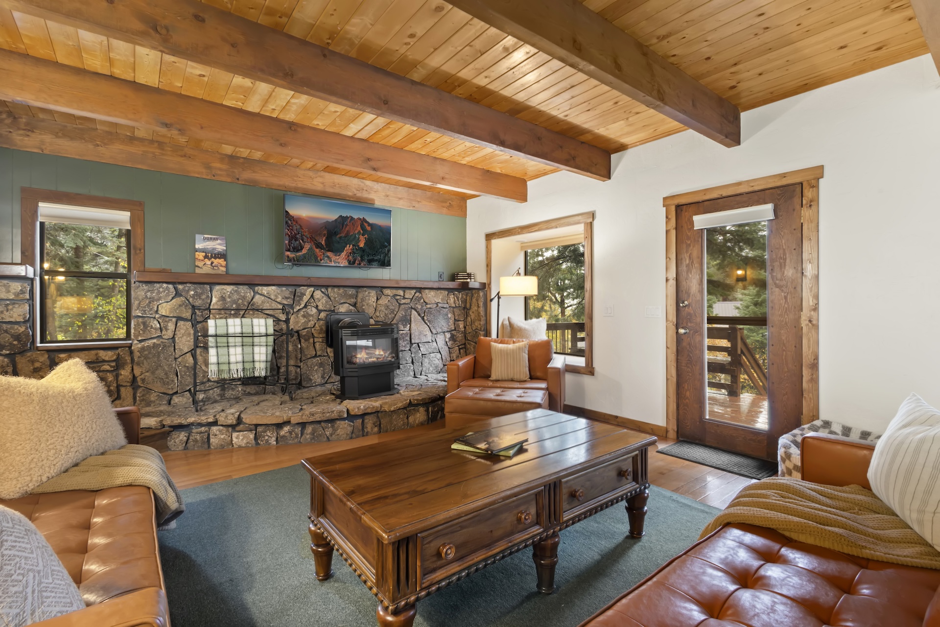 Expansive living room with plenty of seating, bay windows, traditional rock hearth, electric stove and smart TV.