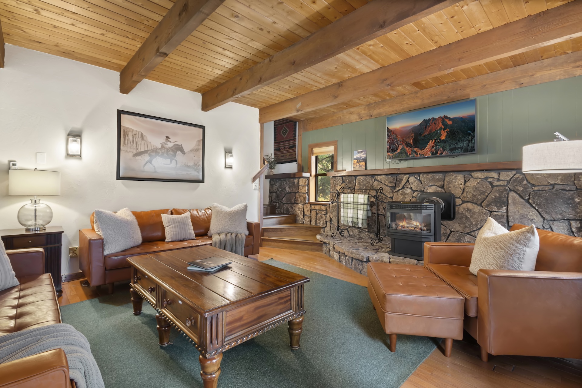 Expansive living room with plenty of seating, bay windows, traditional rock hearth, electric stove and smart TV.