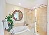 Unwind in the spa-style bathroom featuring a deep soaking tub, walk-in shower, and warm tile finishes. Whether it’s post-beach cleanup or a little extra self-care, this space makes it easy to relax.