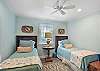 This breezy guest room features two twin beds, a ceiling fan, and light-blocking shutters — perfect for friends, kids, or cousins sharing island dreams.

