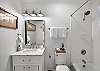 The second full bathroom features a tub/shower combo, marble vanity, and coastal artwork — a calm and comfortable space to rinse off and reset.

