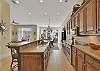 The spacious kitchen at Sea Point Lodge 208 runs the full length of the living area, with granite counters, stainless appliances, and views that stretch all the way to the palms outside.

