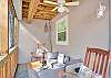 Comfortable screened porch with rocking chairs and cushioned seating—an inviting space to relax, chat, or sneak in a late-night glass of wine beneath the ceiling fan.
