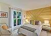 This queen bedroom features a striking golden accent wall, oversized windows, and a quiet mood that makes sleeping in inevitable. Like the rest of this Jekyll Island beach cottage, it’s stylish, sunny, and surprisingly elevated.