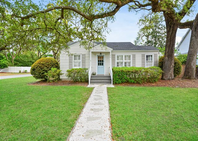 Seagull Cottage front exterior—located at 214 Ashantilly Street in St. Simons Island. Just a short walk to Pier Village, this adorable 2BR rental welcomes guests with mossy oaks, a fenced yard, and quiet island charm.