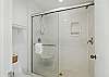 The primary suite's ensuite includes a walk-in shower with glass doors, built-in shelving, and bright overhead lighting. Everything you need to rinse off sand, sunscreen, or that shrimp-and-grits glow.

