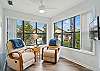 This quiet corner inside 308 Harbour Oaks features two cushioned chairs and panoramic windows—perfect for morning coffee, journaling, or winding down after a day on St. Simons Island.