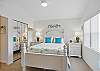This queen bedroom pairs coastal bedding with bright blue pillows and natural light from two windows. It’s a calm, comfortable spot to recharge after shrimp at Iguanas or a sunset stroll through Neptune Park.
